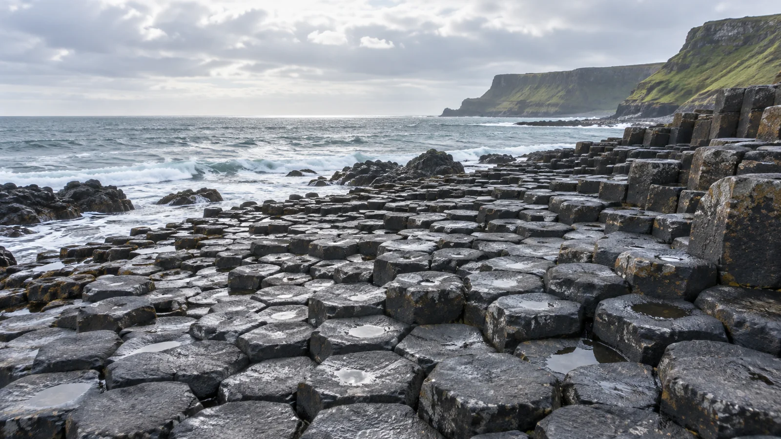 Editorial illustration of dark polygonal basalt columns meeting the Atlantic coast at the Giant’s Causeway.